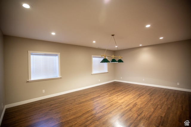 empty room with dark wood-style floors, baseboards, and recessed lighting