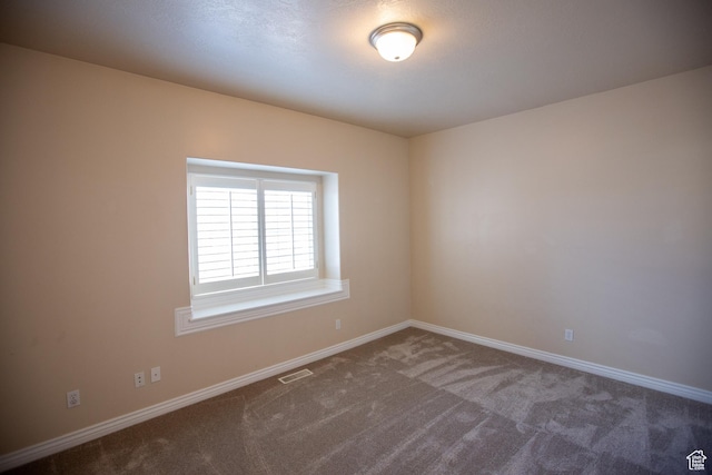spare room with carpet flooring, visible vents, and baseboards