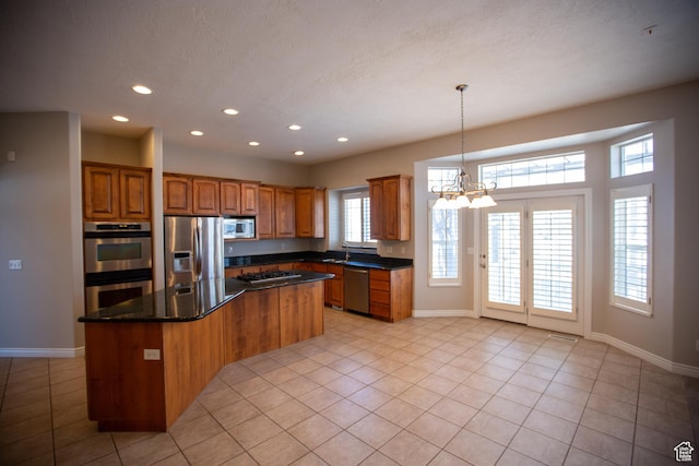 kitchen featuring brown cabinetry, a kitchen island, stainless steel appliances, a chandelier, and a sink