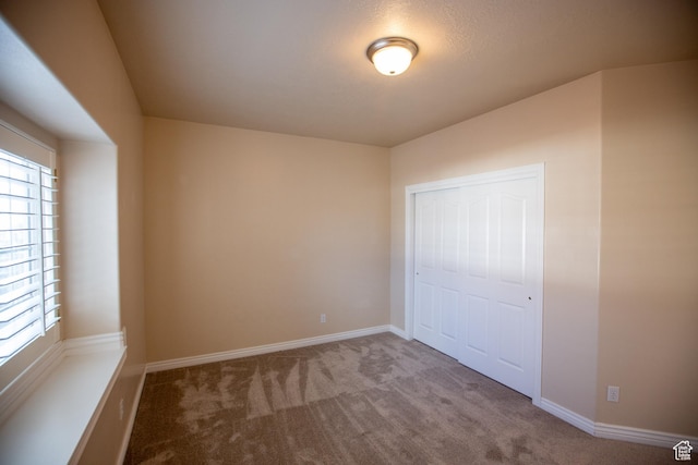 unfurnished bedroom featuring carpet floors, a closet, and baseboards