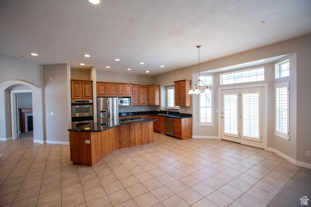 kitchen with stainless steel appliances, dark countertops, a kitchen island, and recessed lighting