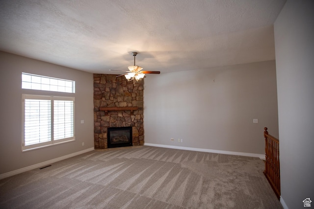unfurnished living room featuring baseboards, visible vents, light colored carpet, a textured ceiling, and a fireplace