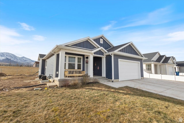 view of front of house featuring a garage, a mountain view, covered porch, and a front yard