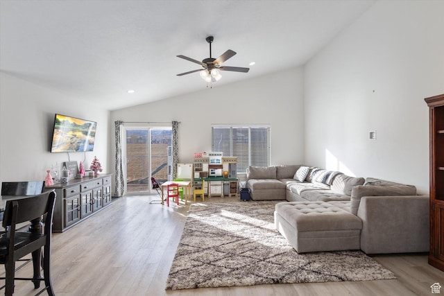living room featuring ceiling fan, lofted ceiling, and light wood-type flooring