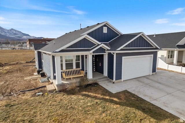 view of front of property featuring a garage, a mountain view, a front yard, and covered porch