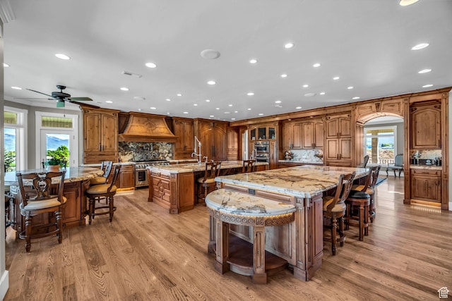 2410 E Center Creek Rd, Heber City, UT 84032 - kitchen with a kitchen bar, custom exhaust hood, stainless steel range, a large island, and decorative backsplash
