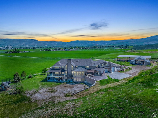 aerial view at dusk featuring a mountain view and a rural view