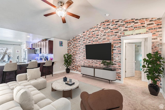 carpeted living room featuring sink, vaulted ceiling, ceiling fan, and brick wall