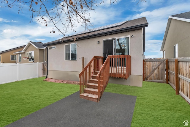 back of property featuring a yard and solar panels