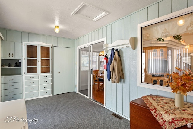 mudroom featuring a textured ceiling and dark colored carpet