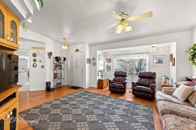 living room featuring ceiling fan, vaulted ceiling, light hardwood / wood-style floors, and a textured ceiling