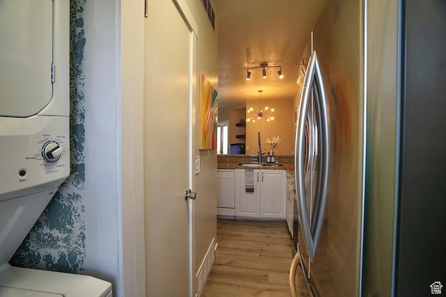 5338 S Beacon Hill Cir W Unit 181, Salt Lake City, UT 84123 - kitchen with stainless steel fridge, white cabinetry, stacked washer and clothes dryer, white dishwasher, and light wood-type flooring