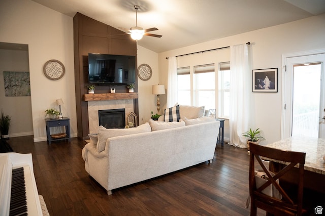 living room featuring dark wood-type flooring, ceiling fan, vaulted ceiling, and a tile fireplace