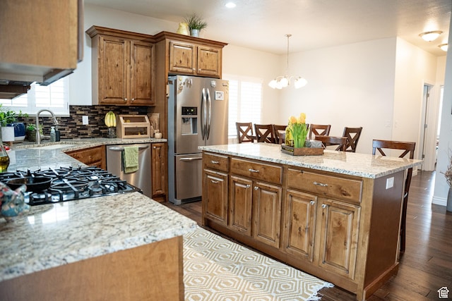 kitchen featuring a kitchen island, appliances with stainless steel finishes, decorative backsplash, hardwood / wood-style flooring, and hanging light fixtures