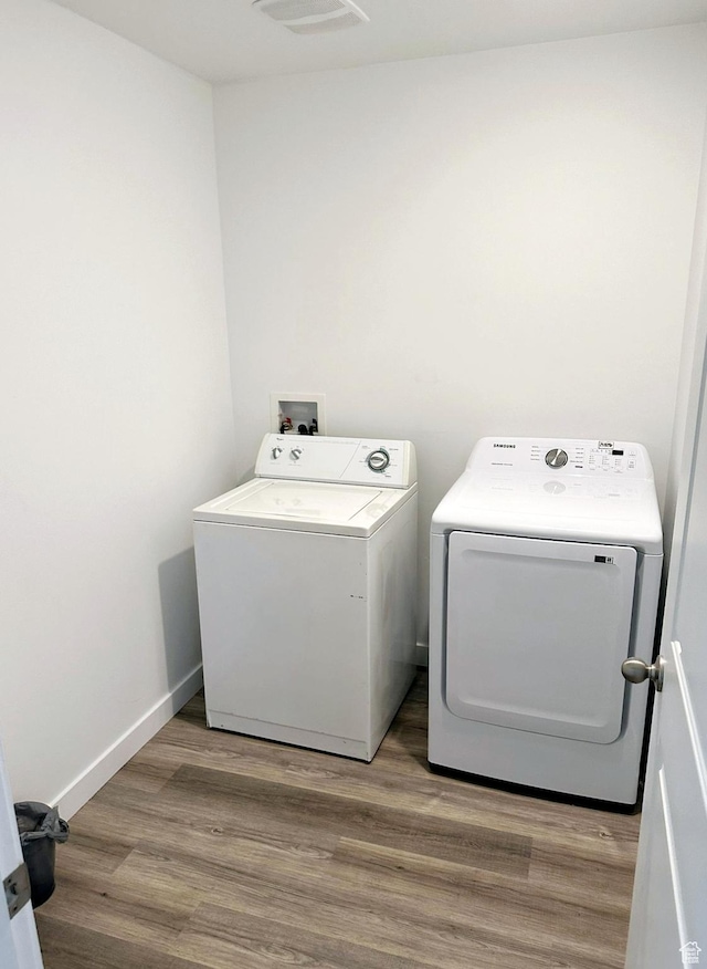 clothes washing area featuring hardwood / wood-style floors and washer and clothes dryer