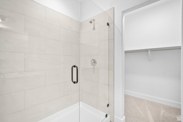 bathroom featuring a shower stall, baseboards, and a walk in closet