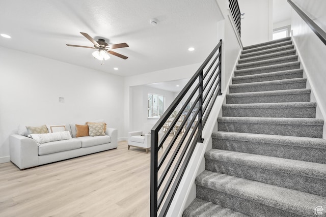 stairs featuring wood finished floors, ceiling fan, baseboards, and recessed lighting