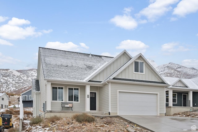 view of front of property featuring a mountain view, driveway, board and batten siding, an attached garage, and a shingled roof