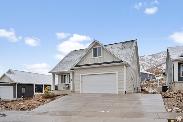 view of front of house with a mountain view, a shingled roof, an attached garage, board and batten siding, and concrete driveway