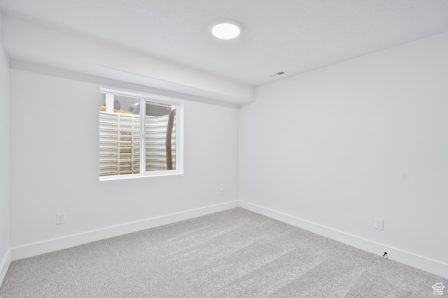 empty room with carpet, visible vents, and baseboards