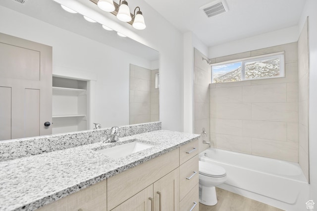 full bath featuring washtub / shower combination, vanity, toilet, visible vents, and wood finished floors