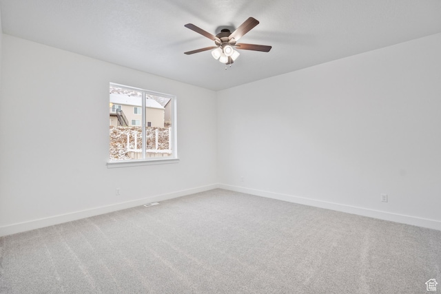 carpeted empty room with baseboards and a ceiling fan