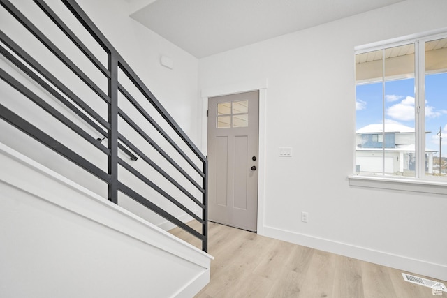 entrance foyer featuring visible vents, baseboards, light wood-style floors, and stairs