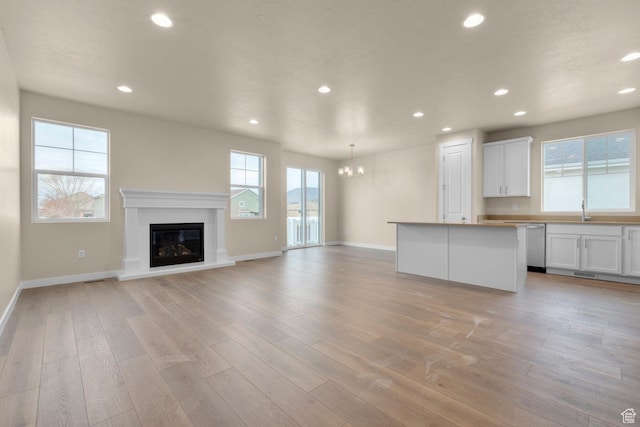 622 W Junegrass Ln, Stansbury Park, UT 84074 - unfurnished living room with a healthy amount of sunlight, sink, and light hardwood / wood-style flooring