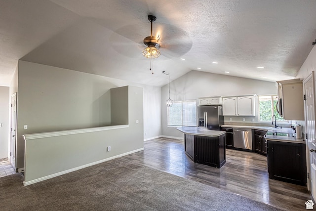 kitchen featuring appliances with stainless steel finishes, hanging light fixtures, white cabinets, a kitchen island, and vaulted ceiling