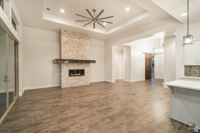 378 W Redstone Ct, Ivins, UT 84738 - unfurnished living room featuring dark wood-style floors, a barn door, a raised ceiling, and a ceiling fan