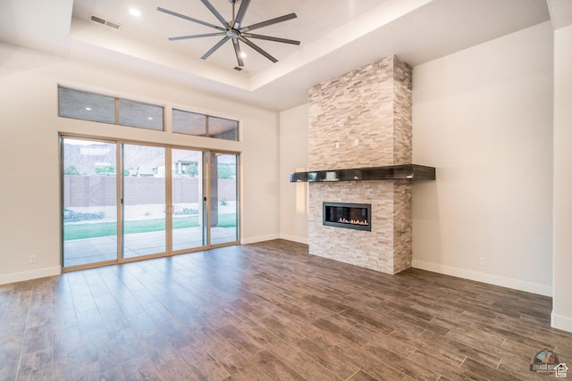 378 W Redstone Ct, Ivins, UT 84738 - unfurnished living room with ceiling fan, a stone fireplace, dark wood-style flooring, baseboards, and a tray ceiling