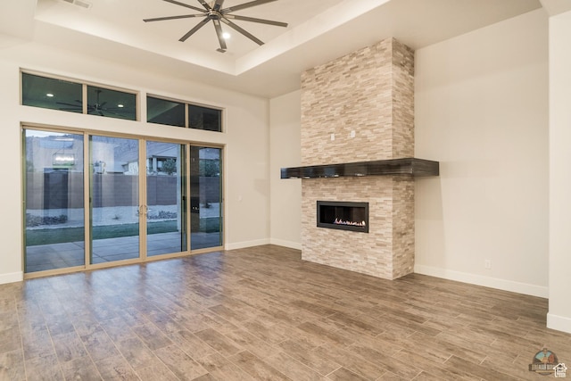 378 W Redstone Ct, Ivins, UT 84738 - unfurnished living room featuring baseboards, a raised ceiling, a tiled fireplace, a ceiling fan, and wood finished floors