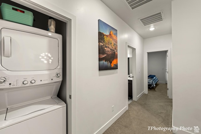 washroom with stacked washer and clothes dryer and light colored carpet