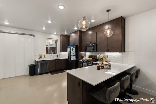 kitchen with hanging light fixtures, kitchen peninsula, dark brown cabinetry, and black appliances