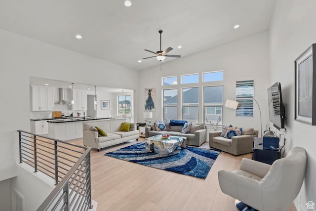 living room featuring a high ceiling, ceiling fan, and light hardwood / wood-style floors