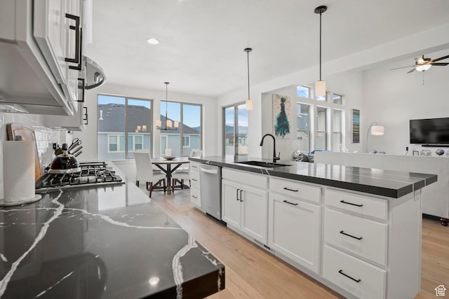 kitchen with white cabinetry, sink, hanging light fixtures, a kitchen island with sink, and stainless steel appliances
