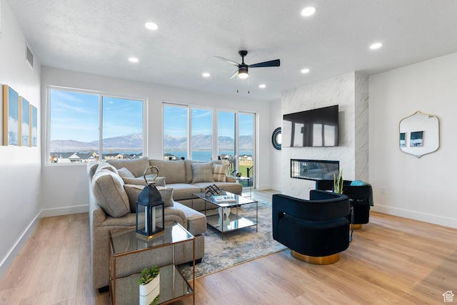 68 E Watson Dr S, Saratoga Springs, UT 84045 - living room with a premium fireplace, ceiling fan, a textured ceiling, and light hardwood / wood-style floors