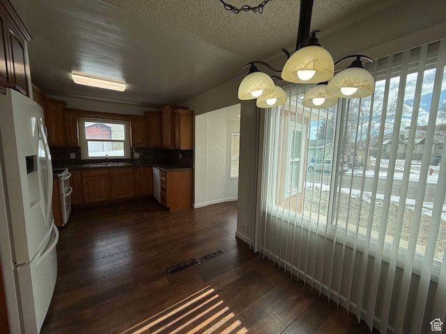kitchen with sink, tasteful backsplash, a textured ceiling, dark hardwood / wood-style floors, and white appliances