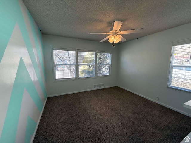 empty room featuring ceiling fan, a textured ceiling, and dark colored carpet