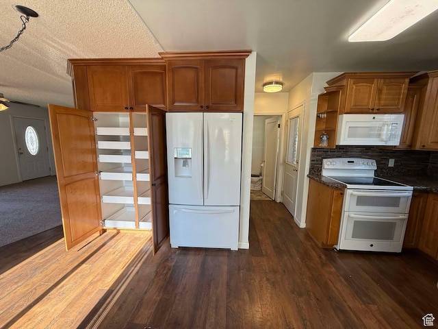 kitchen with dark wood-type flooring, white appliances, and decorative backsplash