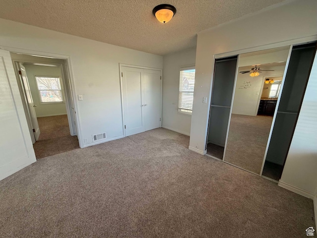 unfurnished bedroom with multiple windows, a textured ceiling, and carpet flooring