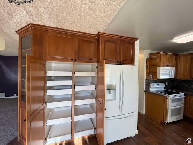 kitchen with dark hardwood / wood-style floors, decorative backsplash, dark stone counters, white appliances, and a textured ceiling