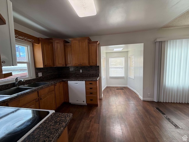 kitchen with dark wood-type flooring, dishwasher, sink, and backsplash