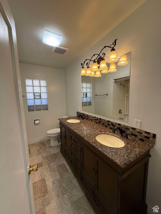 bathroom featuring vanity, decorative backsplash, and toilet