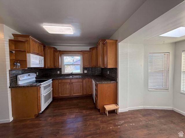 kitchen with sink, white appliances, backsplash, a skylight, and dark hardwood / wood-style floors