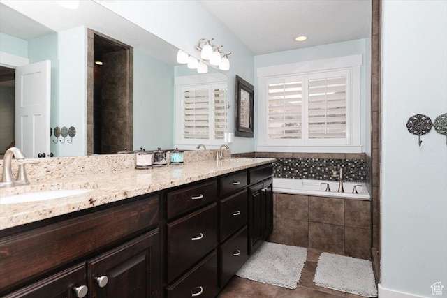 bathroom with tiled tub, vanity, and tile patterned flooring