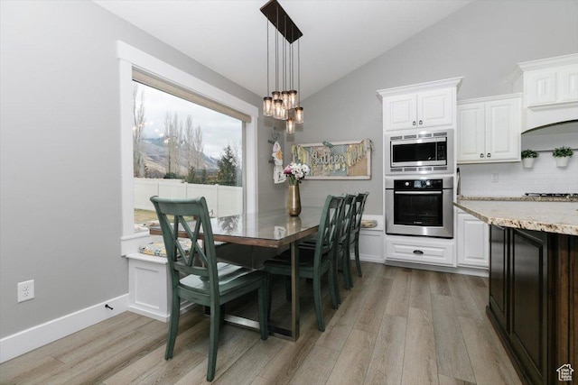 dining room with lofted ceiling, a chandelier, and light wood-type flooring
