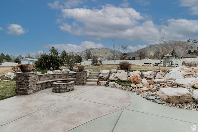 view of patio / terrace with a playground, a mountain view, and a fire pit