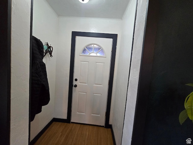 entryway with wood finished floors, baseboards, and ornamental molding