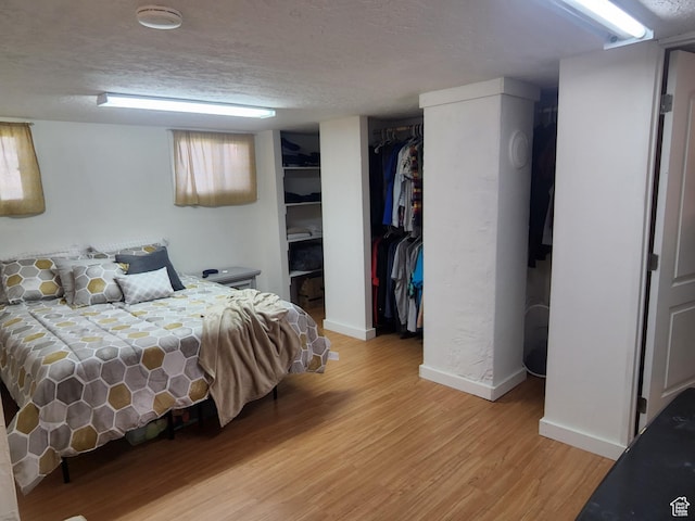 bedroom featuring light wood-type flooring, baseboards, and a textured ceiling